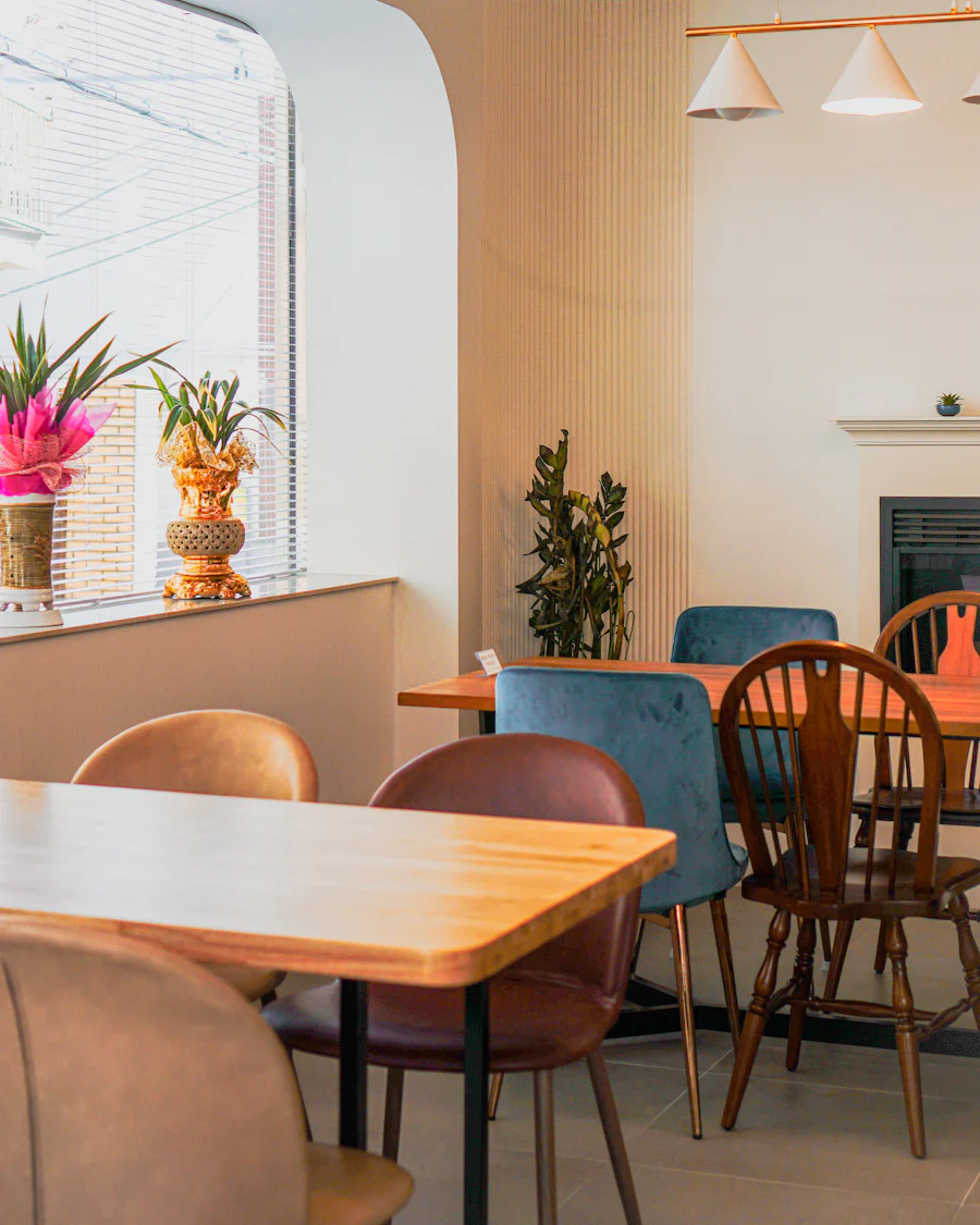 The dining room: a long wooden table, mismatched chairs and plants in the window light.